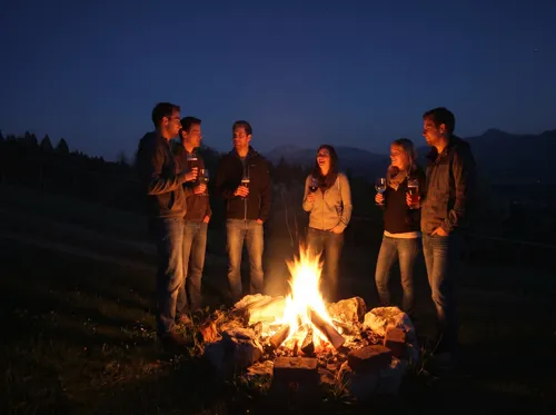 Gäste am Lagerfeuer mit Bergblick am Ferienhaus Huber in der Abenddämmerung