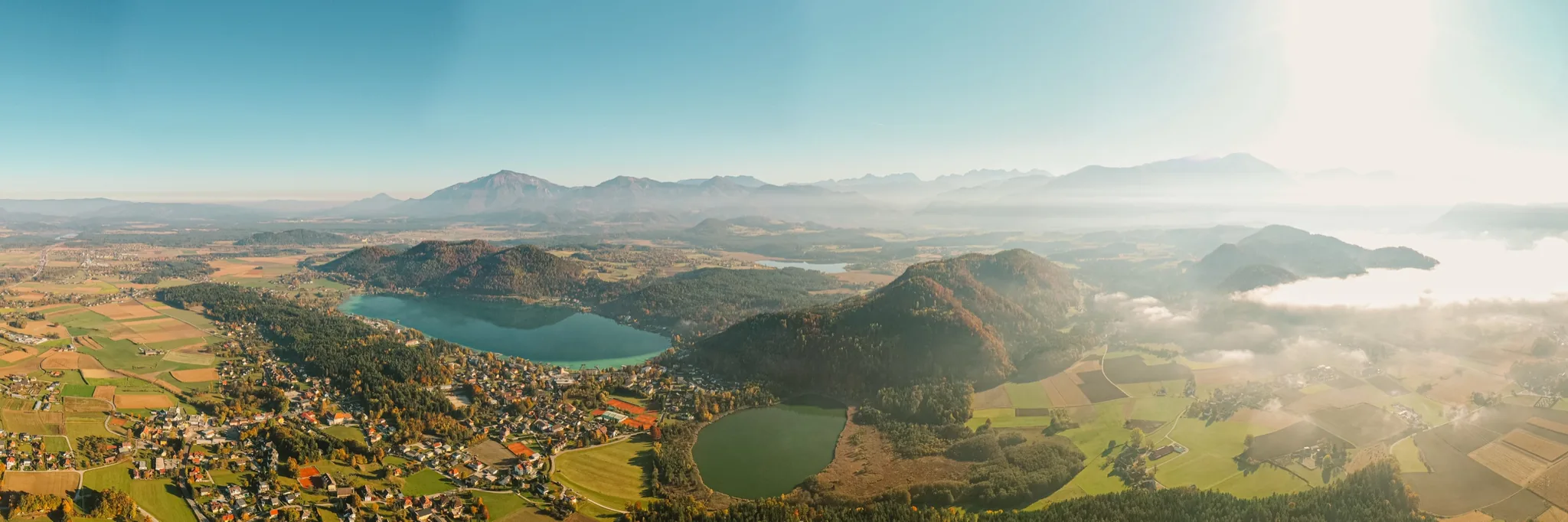 Bunte Herbstlandschaft der Seenregion mit Fernsicht bis zu den Bergen