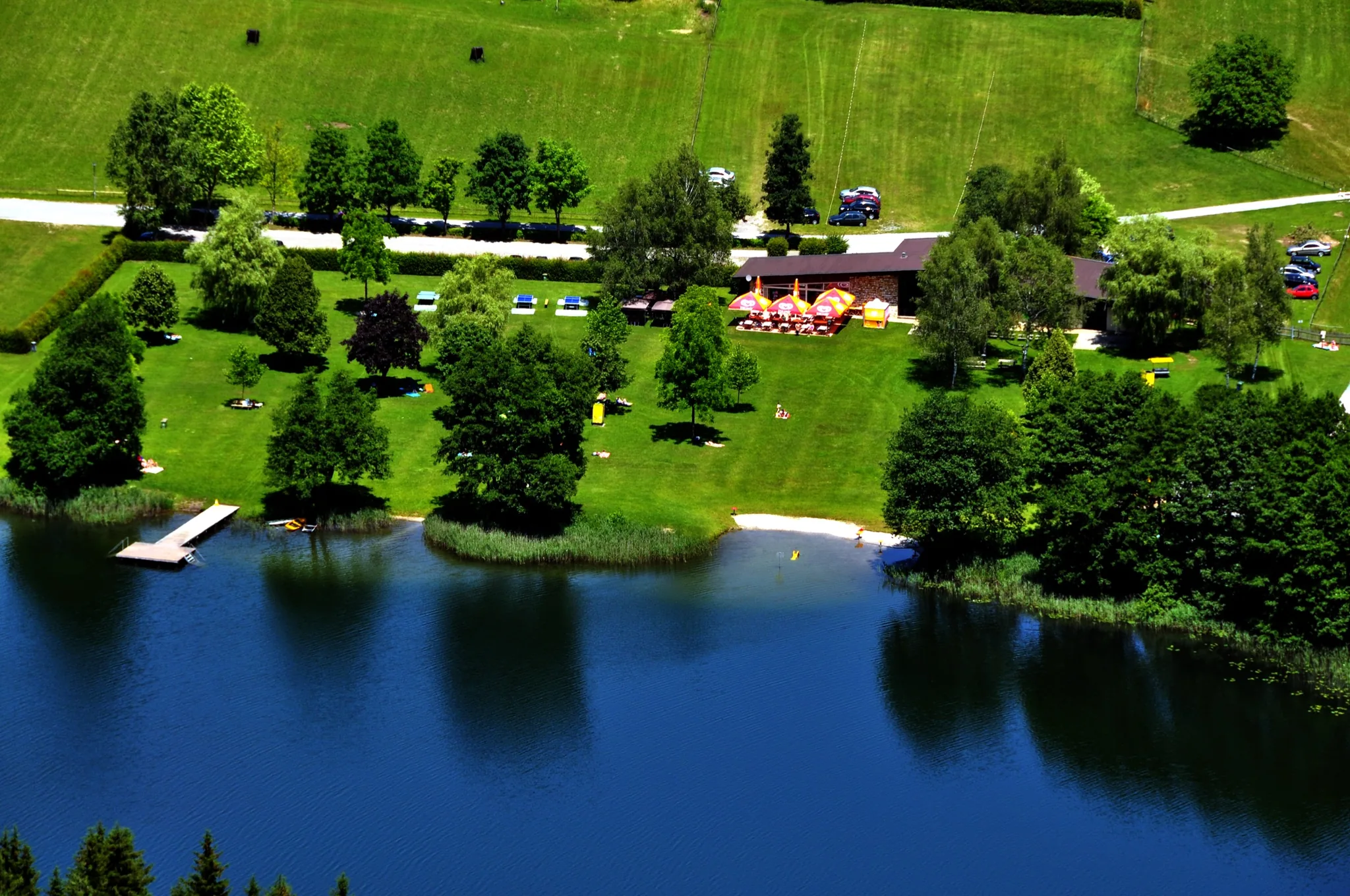 Das Strandbad am Rauschelesee von oben, mit Liegewiese, Steg und flachem Ufer