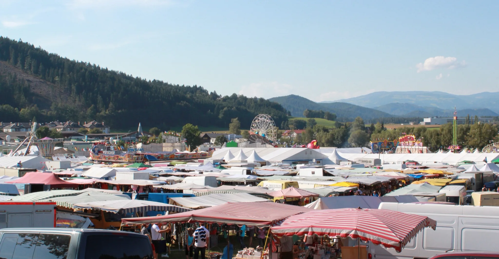 Blick über das Marktgelände des Bleiburger Wiesenmarkts mit Ständen und Riesenrad