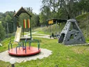Großer eingezäunter Spielplatz mit Rutsche, Karussell und Kletterpyramide