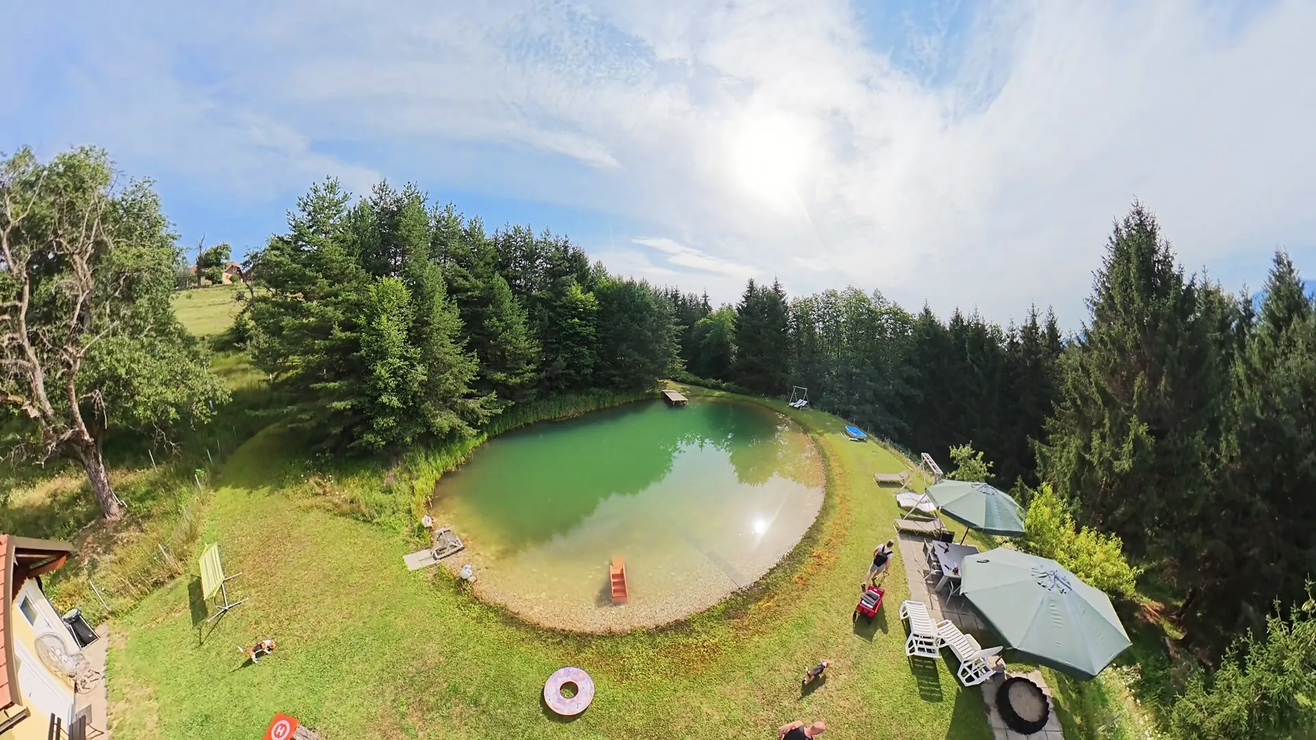 Naturteich mit Sonnenschirmen und Liegewiese rundherum